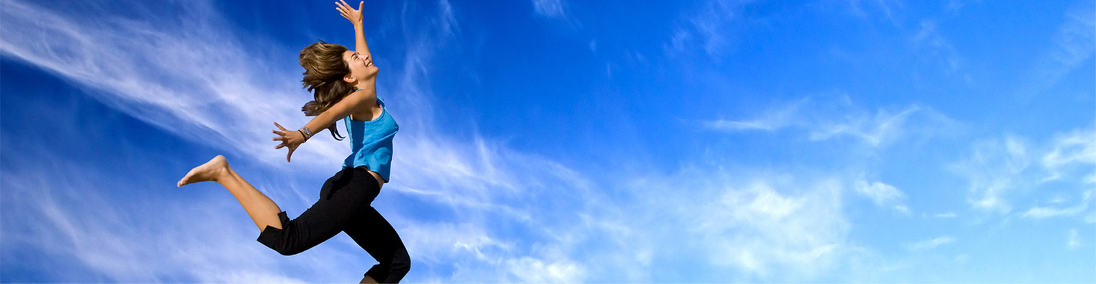 Healthy person happily Jumping against a bright blue sky